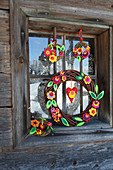 Handmade willow wreaths with felt leaves and felt flowers hung in window