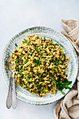 Bulgur pilaf with green lentils and herbs served in a large ceramic bowl