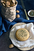 Fresh almond bun with dried herbs placed on napkin on gray tabletop