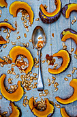 Silver tablespoon and slices of pumpkin on blue background