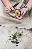 Person peeling fresh artichoke with kitchen knife