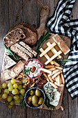 Reichhaltige Käseplatte mit Brot, Oliven, Trauben und Nüssen