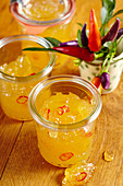 Pineapple and chili jam with purple chillies in a jar on a wooden background