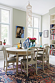 Stylish, white, oval dining table and upholstered chairs in period apartment