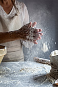 A woman sprinkling flour on a marble surface