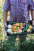A man holding a crate of freshly harvested vegetables