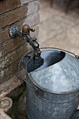 Watering can under ornate garden tap