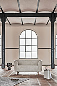 Modern, oval sofa in old factory building with metal pillars