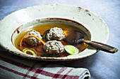 Liver dumpling soup with vegetables on a rustic plate