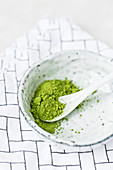 Matcha tea powder in a ceramic bowl with a spoon