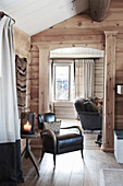 Armchair in front of open doorway leading into living room in wooden house