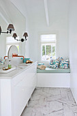 Window seat in small white bathroom