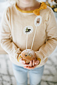 Kind hält mit Papiersteckern dekorierten Muffin in den Händen