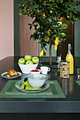 Charcoal-grey island counter used as breakfast table with decorative lemon tree planted in centre