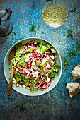Colourful couscous salad with beetroots, fresh spinach and feta cheese. Salad is sprinkled with hazelnuts and dill