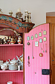 Crockery in farmhouse cupboard with religious pictures on inside of open door