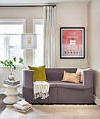 Purple sofa below framed advert and white side table below window