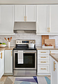 White kitchen with light wood accents, stainless appliances and white subway tiles