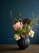 Wintry flower arrangement against dark blue wall