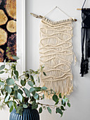 Knotted wall-hanging suspended from branch
