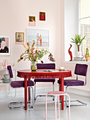 Violette Polsterstühle um roten Tisch mit Fransenborte
