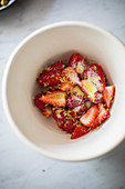 Kleingeschnittene gezuckerte Erdbeeren mit Zitronenschale im Schälchen