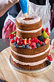 Wedding cake with layers of almond cales, raspberry buttercream, raspberry filling, and fresh fruit