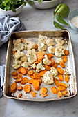 Roasted cauliflower florets and carrot slices on a baking tray