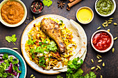 Close-up of assorted traditional Indian dishes, top view of biryani chicken with basmati rice, naan bread