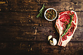 Raw marbled meat steak, pepper, herbs, garlic, old wooden background