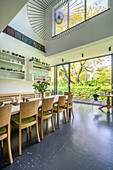 Dining area next to glass wall in high-ceilinged room