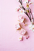 Rosa Petit Fours dekoriert mit Blüten auf rosafarbenem Untergrund