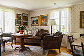 Collection of paintings above brown leather sofa in vintage-style living room