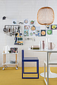 Checked wallpaper in kitchen with utensils on wall, serving trolley, table and chair