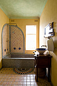 Mosaic-tiled bathtub in Oriental bathroom with yellow walls