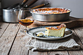 Cottage cheese baked pudding served on plate and glass of cognac on towel against wooden table