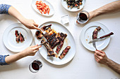 Zwei Personen am Tisch mit Rib-Steak, Garnelen und Rotwein