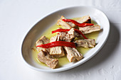 From above marinated tuna with red pepper and oil served on white texture background