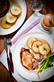 Pork chop with caramelised apple slices and fried spring onions