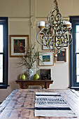 Rustic wooden dining table below wrought-iron chandelier