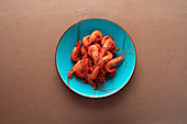 From above ready appetizing prawn in blue plate on brown background