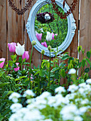 Vintage mirror and suspended rusty hearts behind bed of tulips