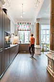 Woman walking through open-plan kitchen with stucco ceiling in Wilhelmine-era villa