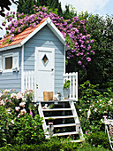 Baumhaus mit Rose 'Veilchenblau' auf dem Dach