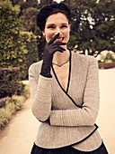 A dark-haired woman wearing a black hat and a beige jacket