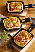 Mini, oven-baked raclette pizzas with cheese and vegetables