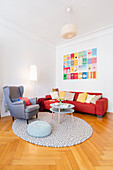 Scatter cushions on red sofa, wing-back chair and coffee table in living room