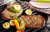 Marinated beef steaks with vegetables on a grill rack