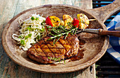 Marinated, grilled rib-eye steak with coleslaw and potato skewers on a wooden plate