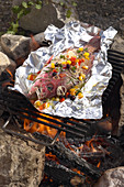 A whole red snapper in aluminium foil on a barbecue